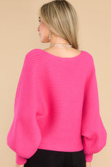 Back view of this sweater that features a scoop neckline, long dolman sleeves, large ribbed knitting, and a cropped style.
