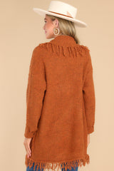 Back view of this cardigan that features a folded neckline, fringe detailing, and long sleeves with ribbed cuffs.
