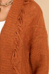 Close up view of this cardigan that features a folded neckline and fringe detailing.