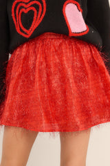 This all red skort features a high rise design, a zipper in the back, shorts in the lining, and fun shiny tinsel detailing throughout.