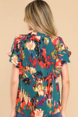 Back view of this top that features a v-neckline, three functional buttons at the front of the bust, ruffled sleeves, and a vibrant pattern throughout.