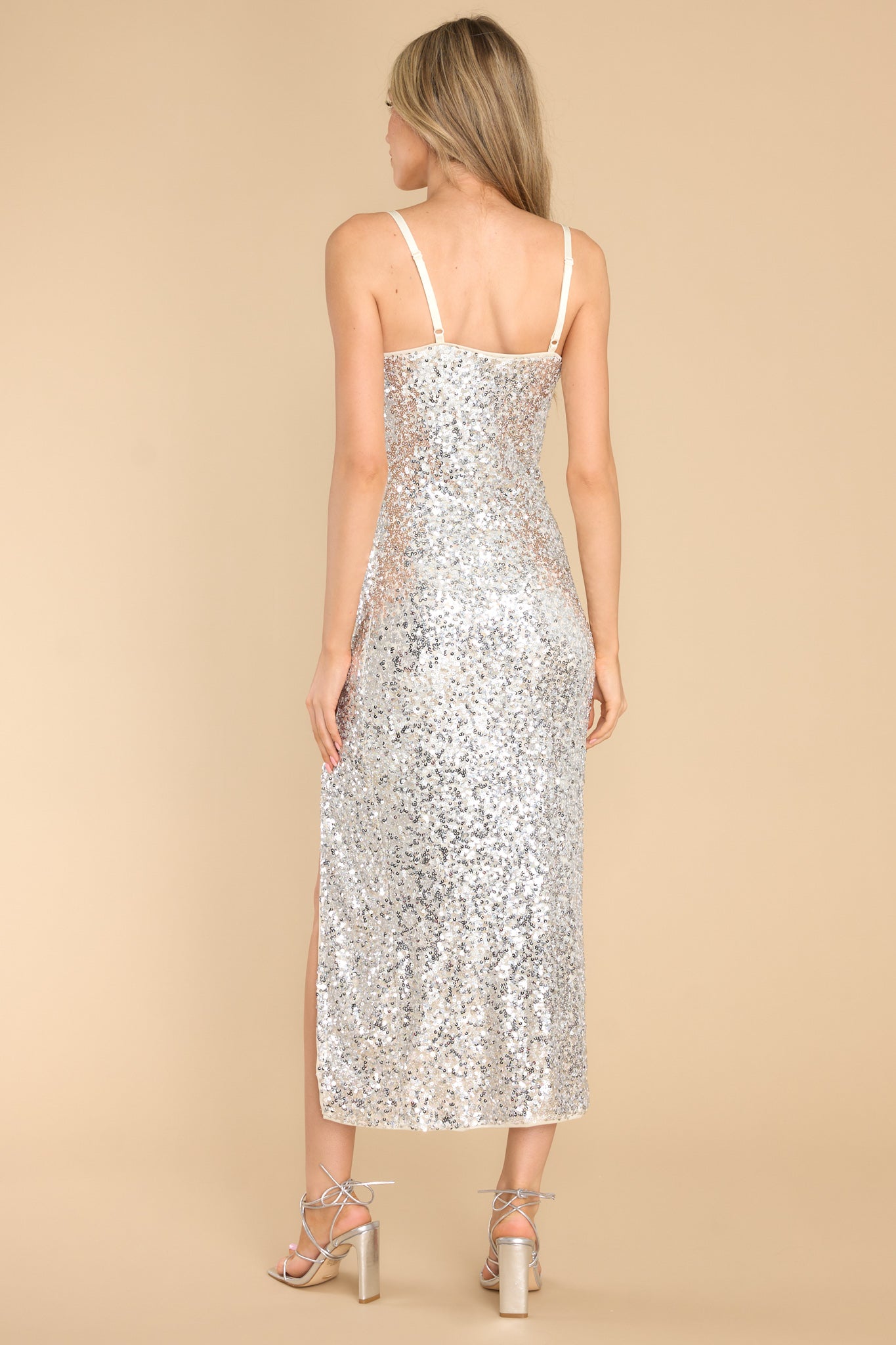 Back view of this dress that features a cowl neckline, adjustable spaghetti straps, full body sequin detailing, and a front slit.