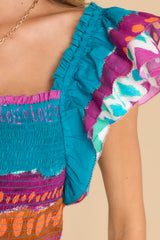 Close up view of this top that features a square neckline, flutter sleeves, and a smocked bodice.