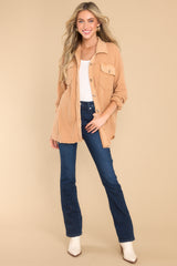 This camel colored top features a collared neckline, functional buttons down the front, bust pockets with button closures, long sleeves with buttoned cuffs, and a mixed-textured design throughout.