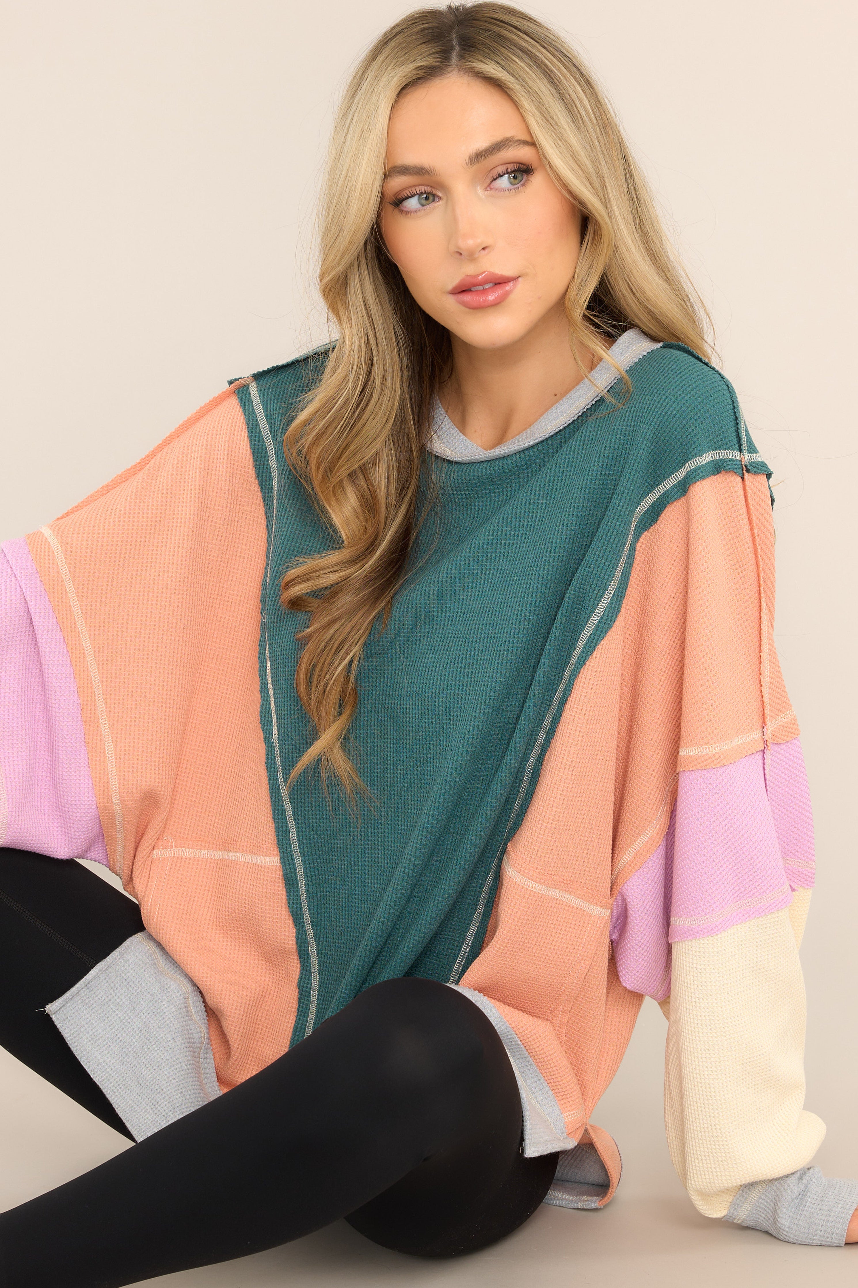 This  multi-colored top features a crew neckline, dropped shoulders, front pockets, a waffle knit material, cuffed sleeves, and a high-low split hemline. 