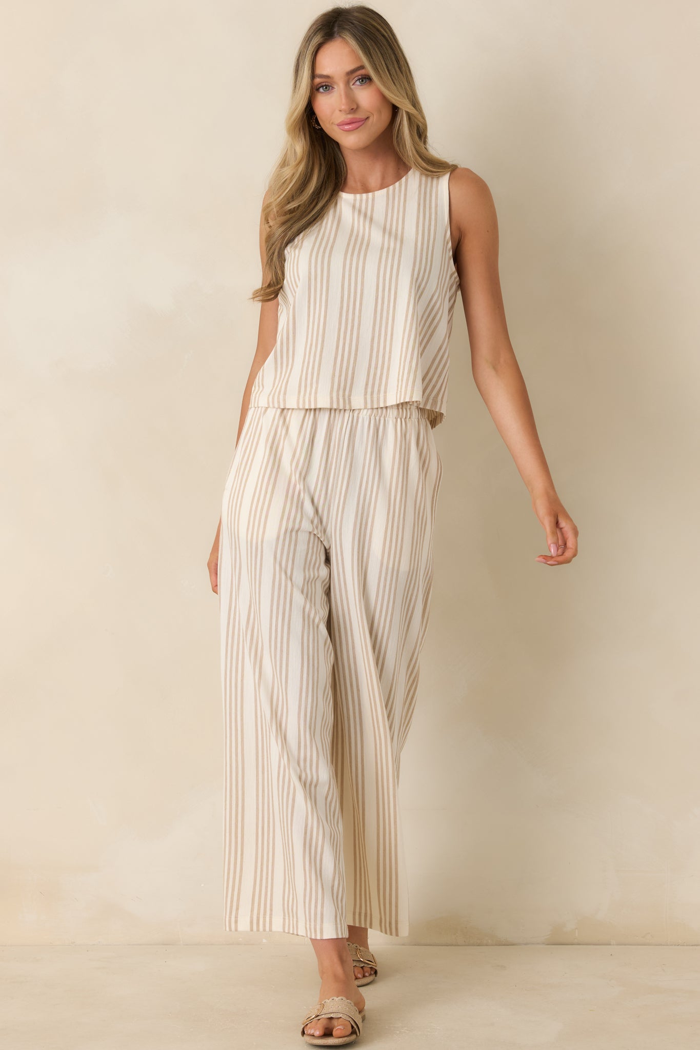 Sleeveless ivory and tan knit top showcasing a relaxed silhouette and timeless horizontal stripe pattern.