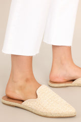 Close up view of these sandals that feature a pointed toe, slip-on design, and a cream, woven detail on the top. 