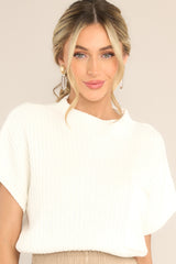 This ivory sweater features a high neckline, a chest pocket, short sleeves, and a ribbed texture.