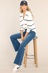 This white and blue cardigan features a v-neckline, a functional button front, functional pockets, ribbed cuffed long sleeves, and a ribbed hemline.