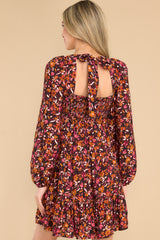 Back view of this dress that features a square neckline, a self tie at the back of the neck, a smocked insert on the back, flowy sleeves with elastic cuffs, and a tiered skirt.