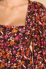 Close up view of this dress that features a square neckline, a self tie at the back of the neck, a smocked insert on the back, flowy sleeves with elastic cuffs, and a tiered skirt.