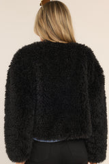 Back view of this faux fur plush jacket that features a rounded neckline, elastic cuffs, two front waist pockets, and snap buttons with an asymmetrical closed front.