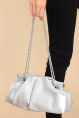 This silver bag features a wide hinged opening that snaps shut (no zipper or snap button closure) , a non-removable silver chain strap, and one zipper pocket inside.