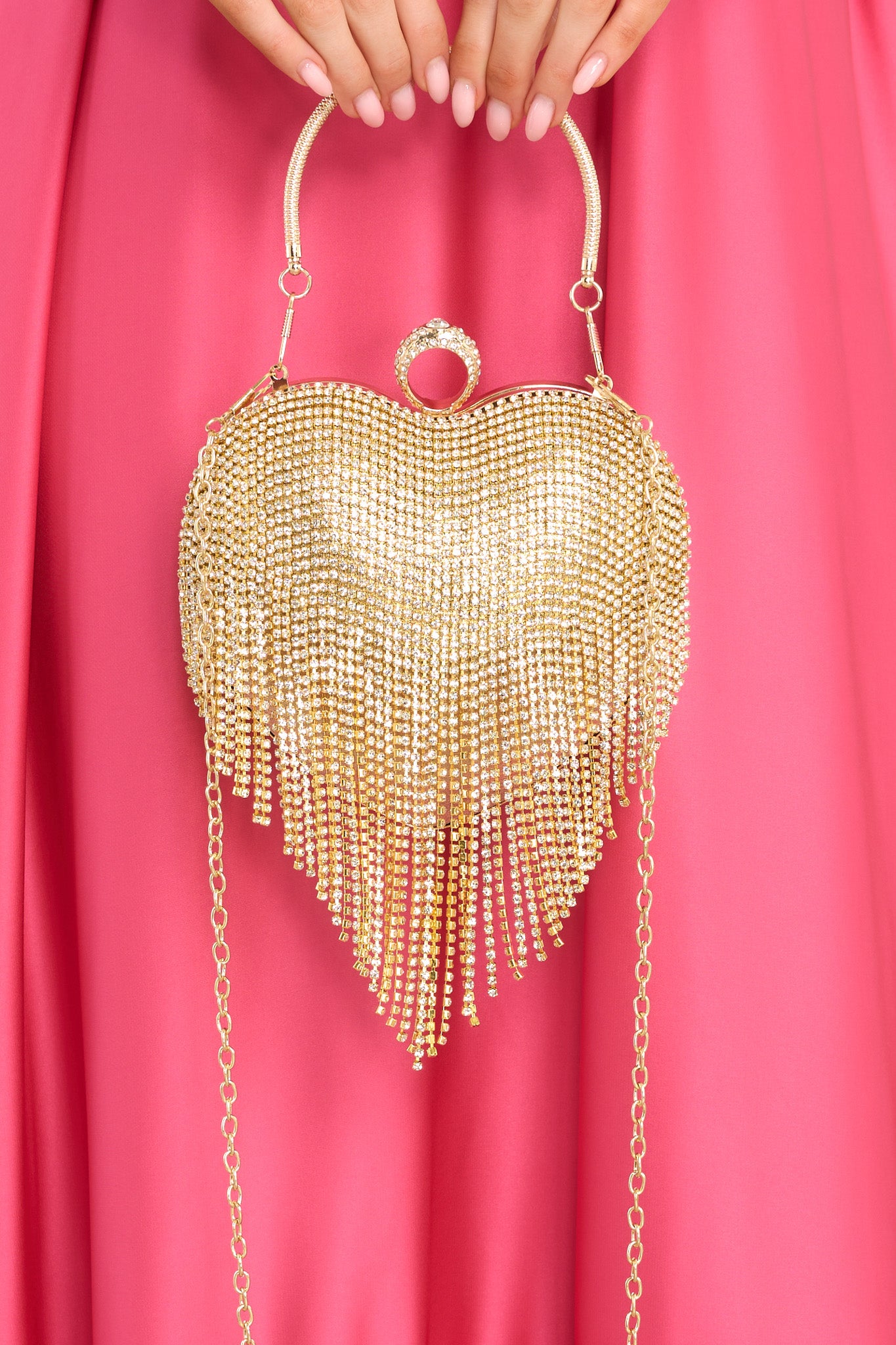 This gold handbag features gold hardware, rhinestone fringe, a removable chain strap, a ring like feature, and a snap closure.
