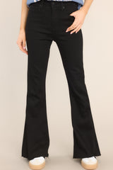 Close-up view of Black Stretch Flare Leg Jeans that feature a standard zipper button closure, functional belt loops, a high waist style, and boot cut hemming. 