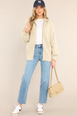  This beige jacket features a functional full zipper, a turtleneck, cozy knit material, and an oversized fit.