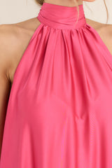 Close up view of this dress that features a halter neckline with a self adjustable tie around the neck, a flowy long silhouette, and a tiered bottom. 