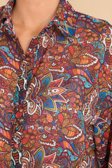 Close up view of this blouse that features a collared neckline and bohemian print in shades of red, orange, yellow, blue, purple, pink, and white.