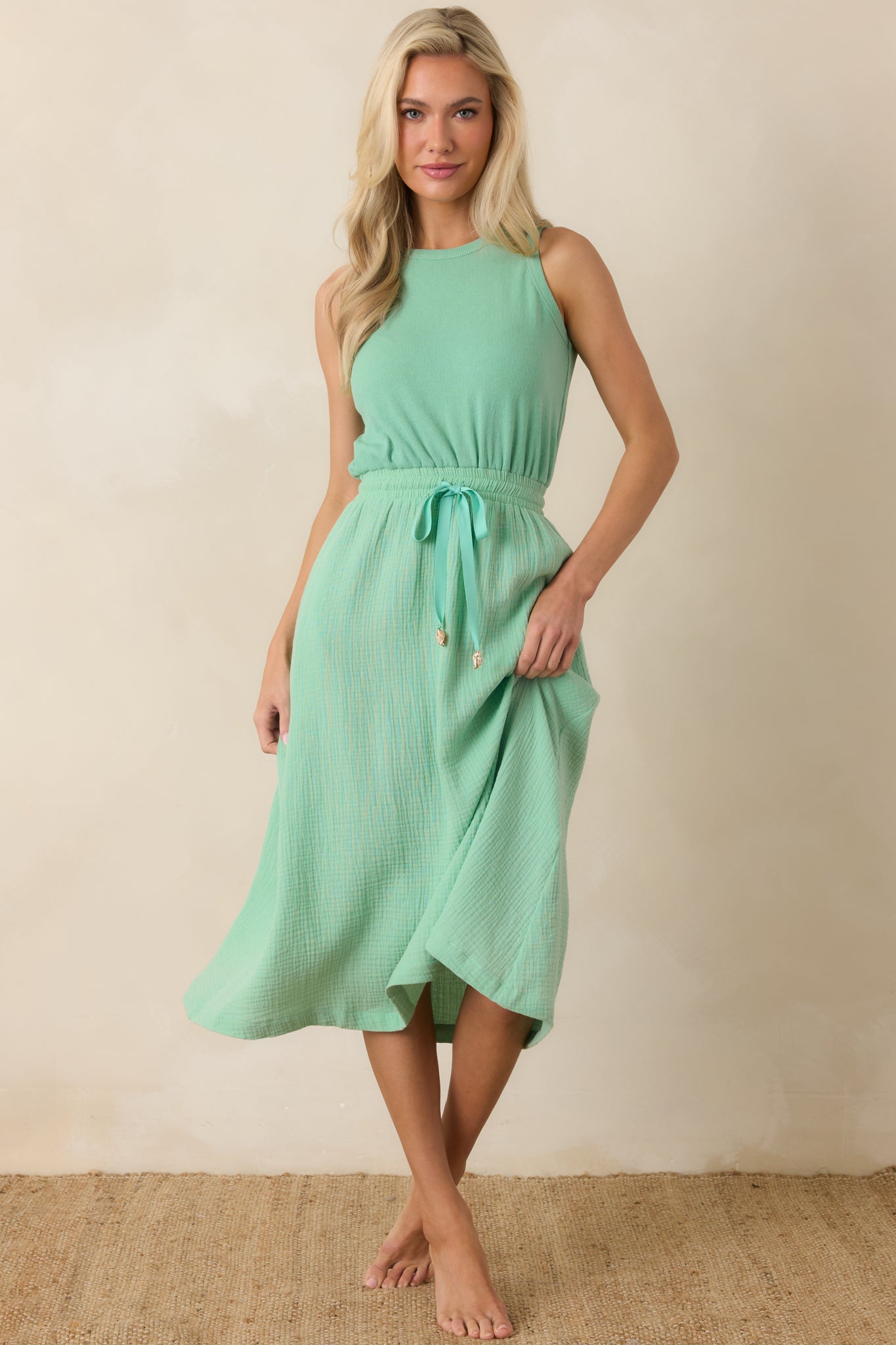 Sleeveless midi dress with a round neckline and softly cinched waist creating a relaxed, flowing shape.
