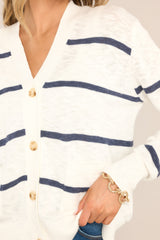 Close up view of this cardigan that features a v-neckline, a functional button front, functional pockets, ribbed cuffed long sleeves, and a ribbed hemline.