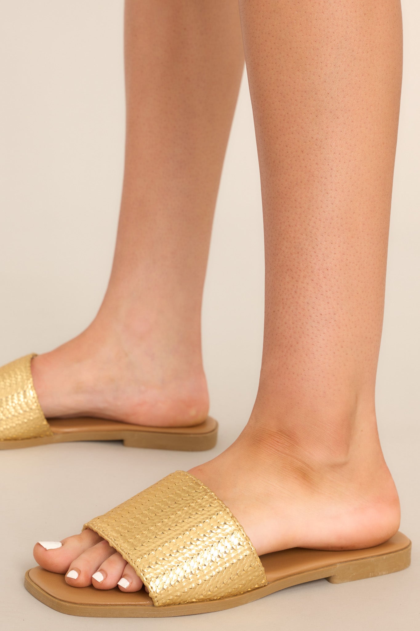 These gold sandals feature a gold detailed strap over the foot and a slip-on style. 