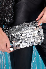 This silver bag features mirror silver discs, a zipper closure, a short shoulder strap, and a gold chain shoulder strap.
