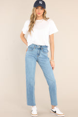 Full body view of these jeans that feature a high waisted design, classic zipper and button closure, belt loops, pockets, light destressing, and a raw hemline.