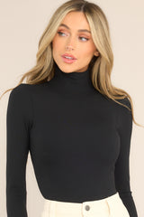 Front view of  this bodysuit that features a turtleneck design, long sleeves, a ribbed texture throughout, and thong-style bottom with a snap button closure.