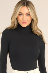 This all black bodysuit features a turtleneck design, long sleeves, a ribbed texture throughout, and thong-style bottom with a snap button closure.