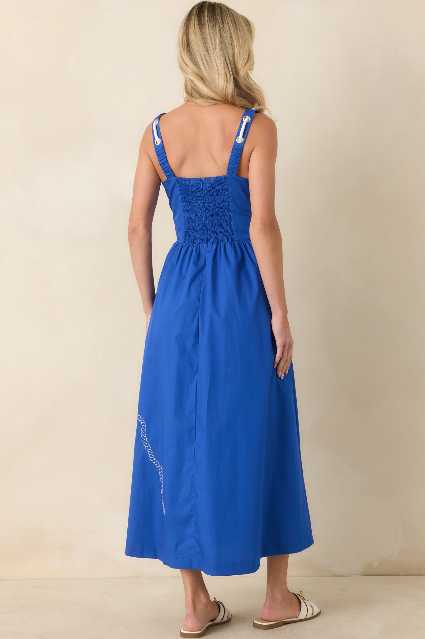 Rear view of the royal blue midi dress featuring a smocked back panel, wide shoulder straps, and a flowing silhouette.