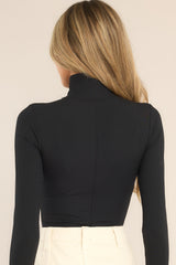 Back view of  this bodysuit that features a turtleneck design, long sleeves, a ribbed texture throughout, and thong-style bottom with a snap button closure.