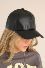 This all black hat features a faux leather material, and an adjustable velcro strap in the back.