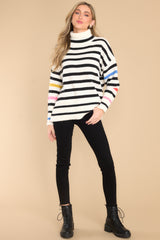 Full body view of this sweater that features a turtleneck, an all-over striped pattern, side slits, and cuffed long sleeves.