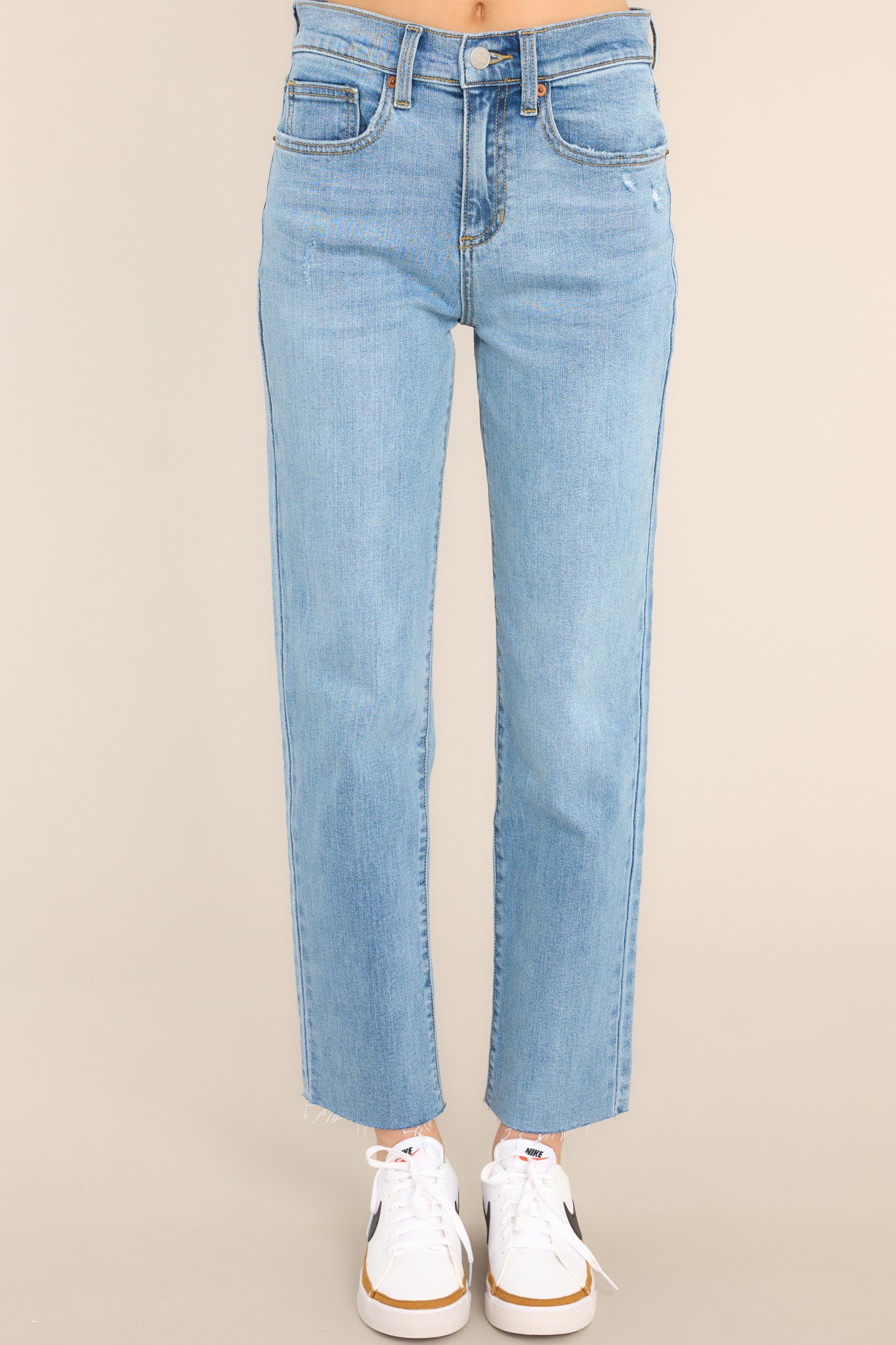 Front view of these jeans that feature a high waisted design, classic zipper and button closure, belt loops, pockets, light destressing, and a raw hemline. 