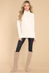 This oatmeal colored sweater features a cowl turtle neckline, long sleeves with ribbed cuffs, and a bottom hem that tapers in around the hips.