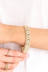 This gold bracelet features gold hardware, watch style band, stretch band, and a slip-on style.