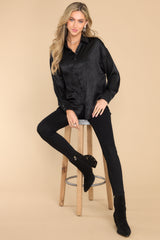 This all black top features a collared neckline, buttons down the front, buttons at the cuff, and a classic relaxed fit.