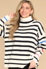Front view of this sweater that features a turtleneck, an all-over striped pattern, side slits, and cuffed long sleeves.