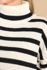 Close up view of this sweater that features a turtleneck and an all-over striped pattern.