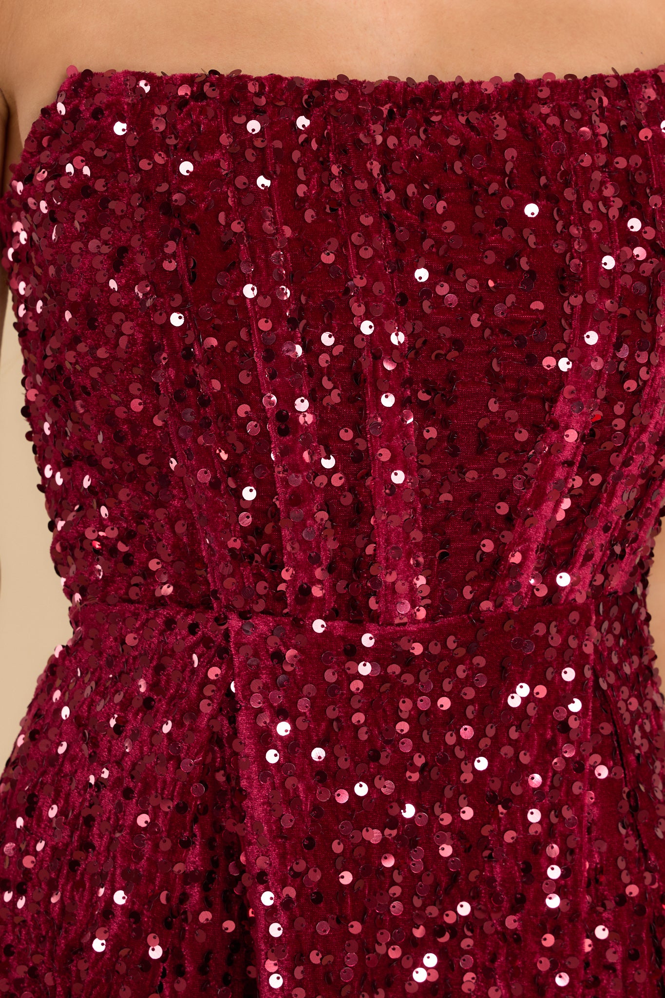 Close up view of this dress that features a strapless neckline, boning in the bodice, faux velvet material, and all over sequin detailing.