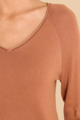 Close up view of this top that features a slight v-neckline with a raw hemline and a soft ribbed material throughout.