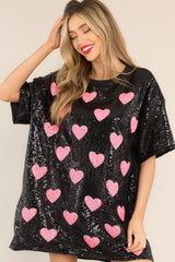 Front view of this tunic that features a round neckline, short sleeves, functional waist pockets, a jersey-style silhouette, colorful sequins throughout, and a fun heart pattern.