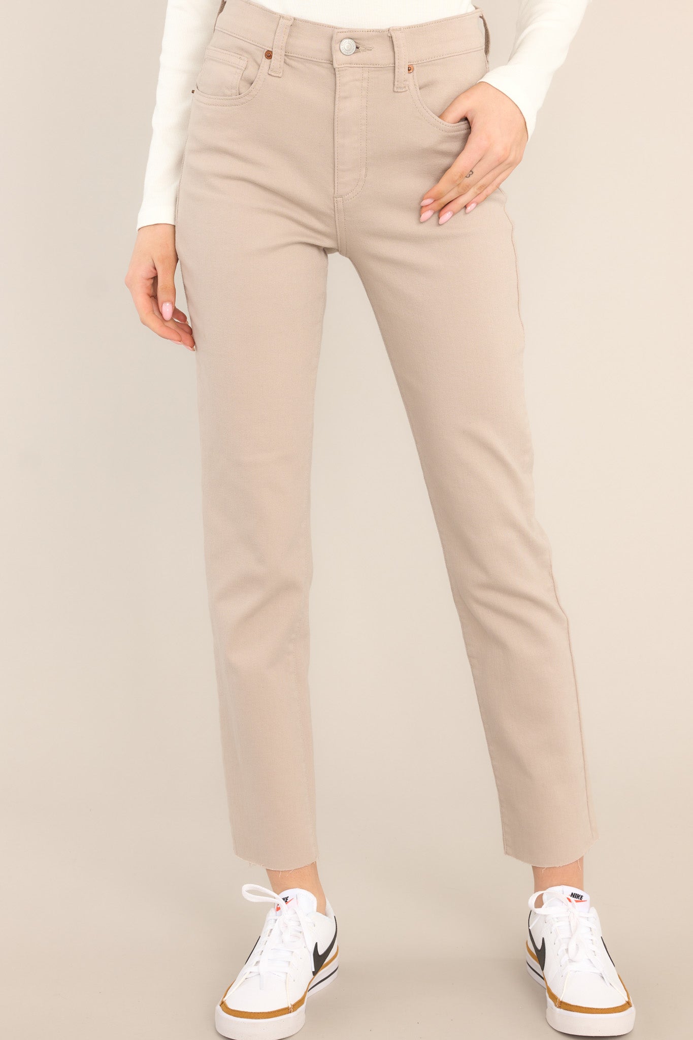 These khaki jeans feature a high waisted deign, a zipper and button closure, functional belt loops and pockets, and a raw hemline. 