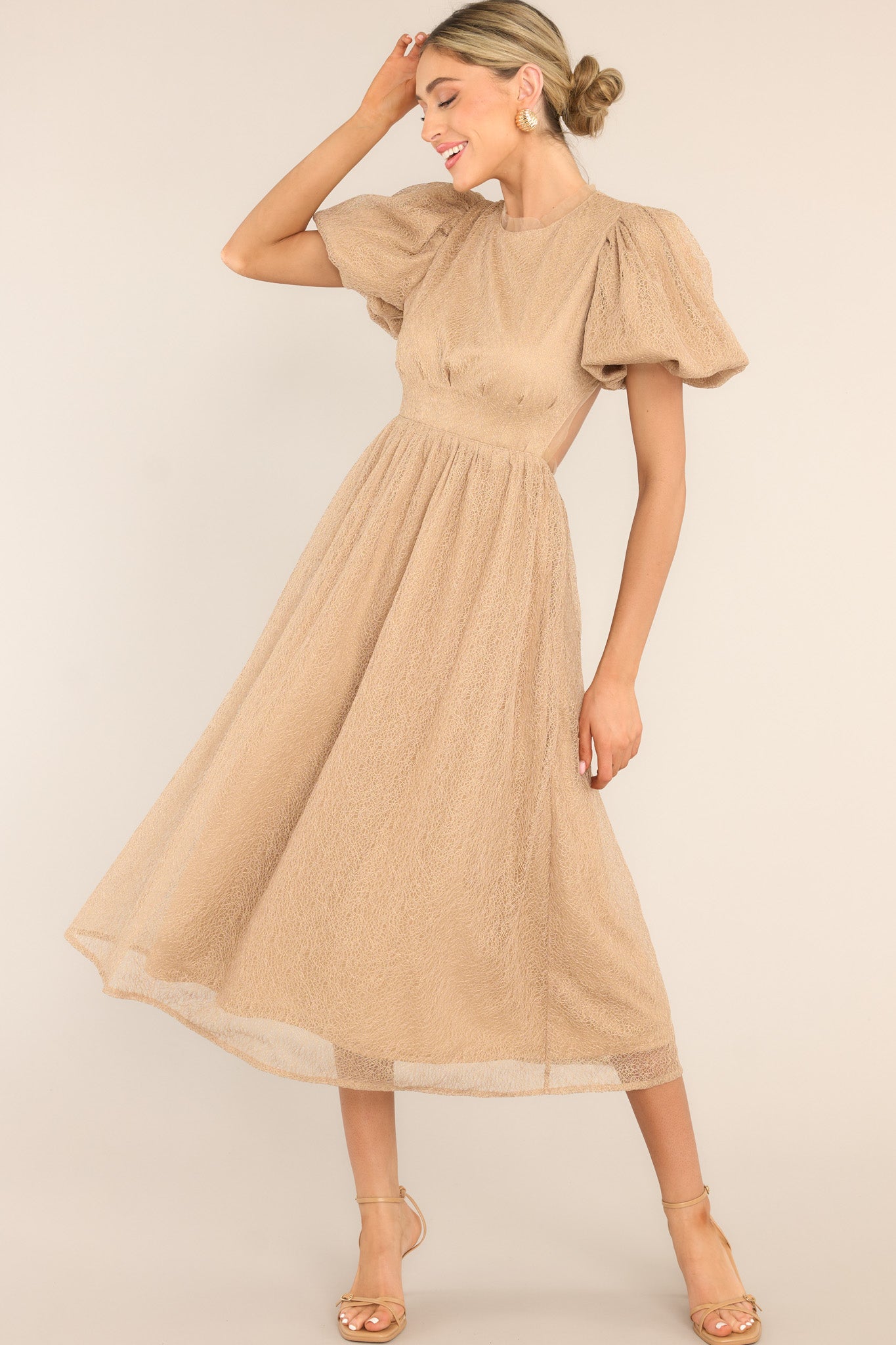 Full body view of this dress that features a round tulle neckline, short puff sleeves, an open back with a four button closure, and a tulle flowy skirt.