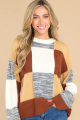 This multi-colored sweater features a crew neckline, patchwork design, and a cozy oversized fit.