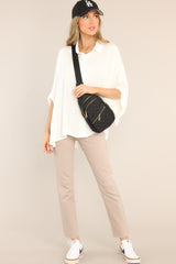 This white top features a collar neckline, functional buttons down the middle, dolman sleeves, and a long fit.