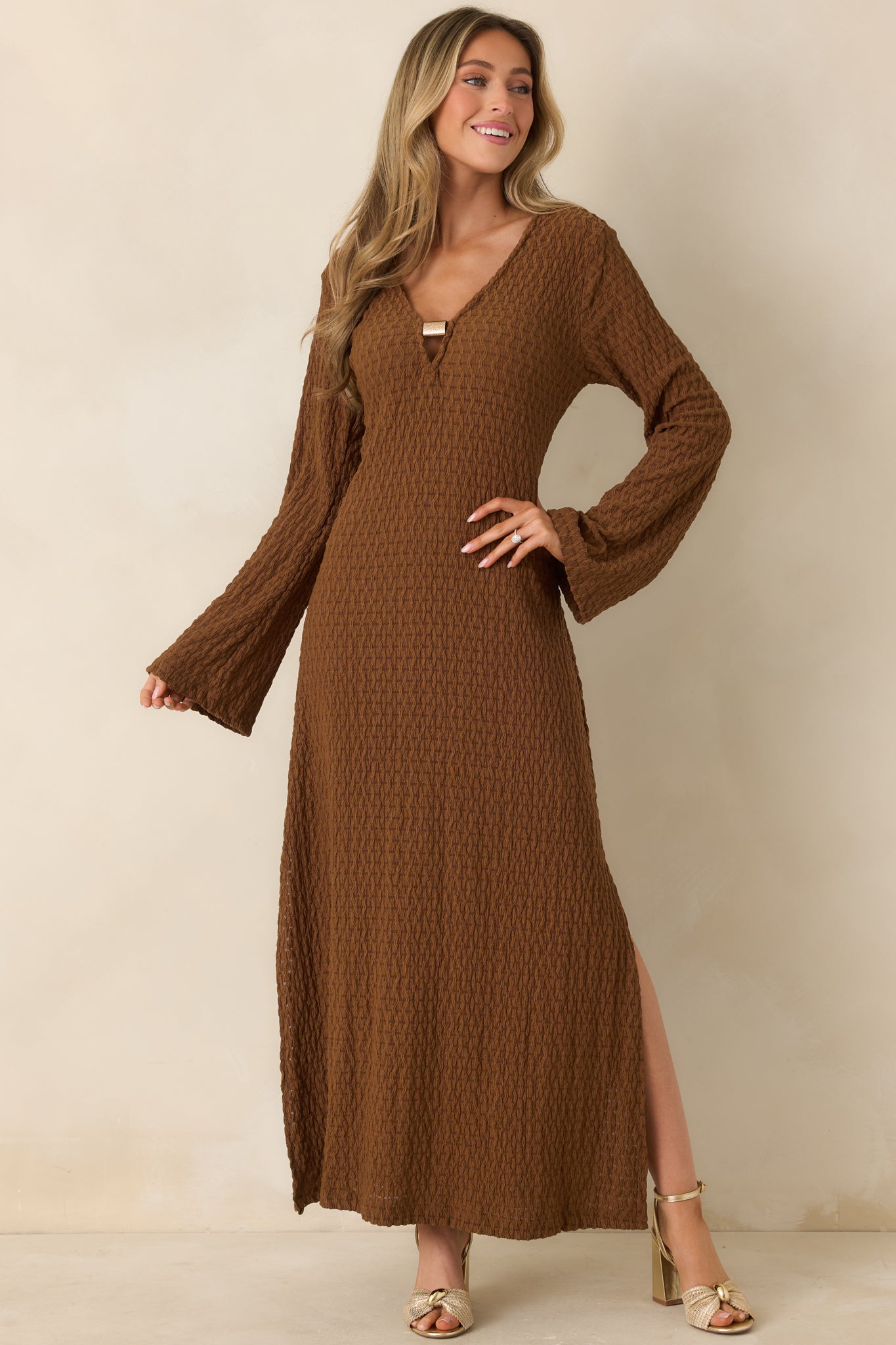 Front view of a brown textured semi-sheer maxi dress with long sleeves and a flowing silhouette.