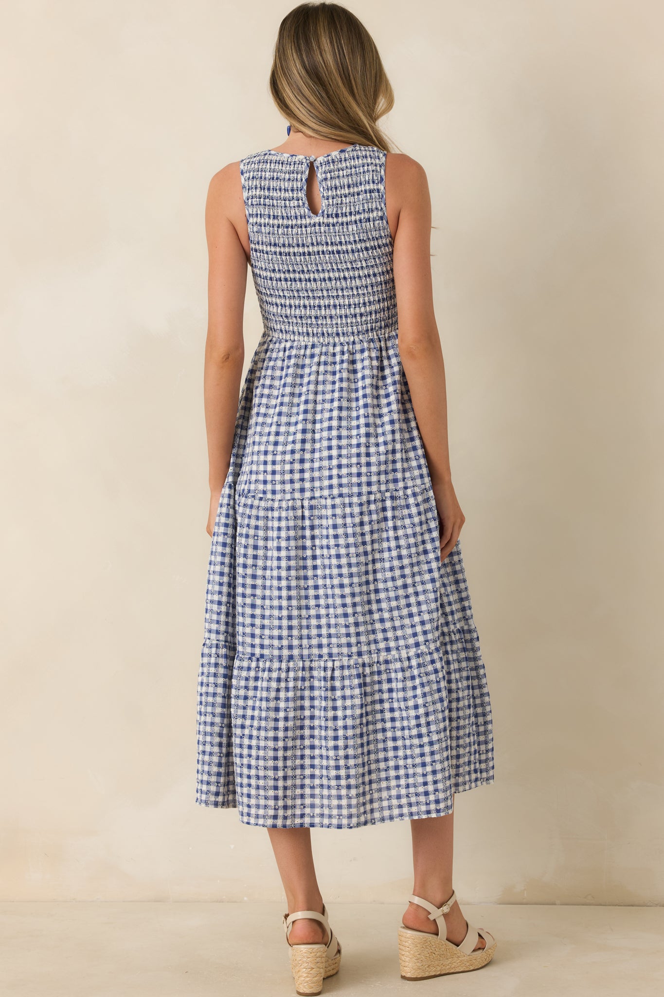 Rear view of blue gingham midi dress featuring a back keyhole button closure and tiered skirt silhouette.