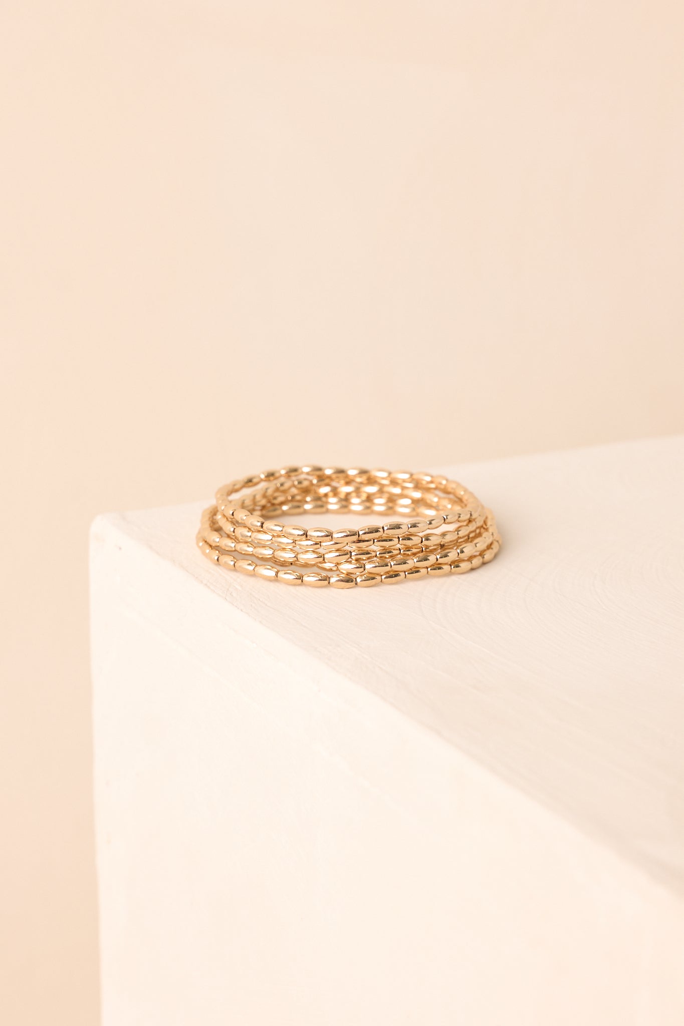 A closer detailed image revealing the polished surface and elongated oval bead design of the gold stretchy bracelets.