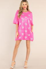 This hot pink tunic features a round neckline, short sleeves, functional waist pockets, a jersey-style silhouette, colorful sequins throughout, and a fun heart pattern. 